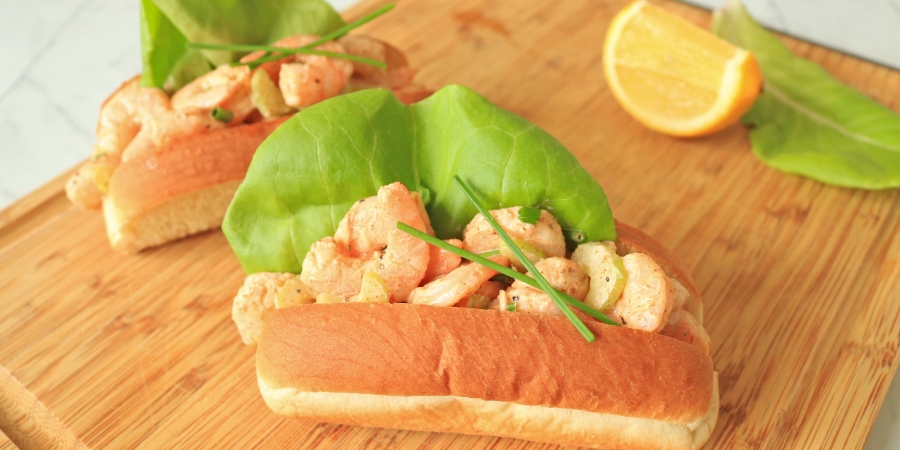 Two shrimp rolls on a cuttingboard.